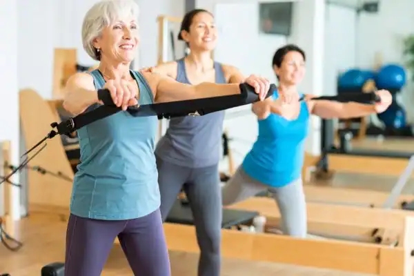 Toning Arms After 60: Empowering Womens Fitness Through Effective Weight Training 2 older woman doing weight training Harwich and resistance in the gym to tone upper arms