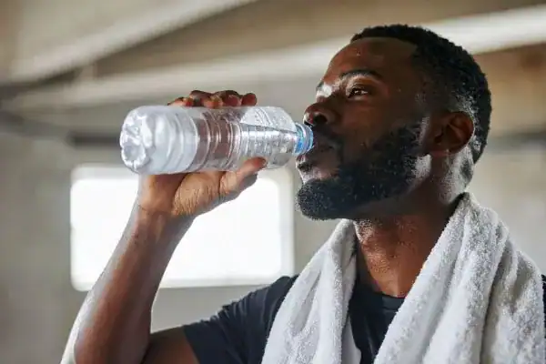 Image of man drinking water to improve hydration Harwich after work out.